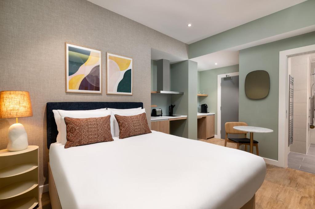 Hotel room with a large bed, two brown throw pillows, bedside lamp, and abstract art above the headboard