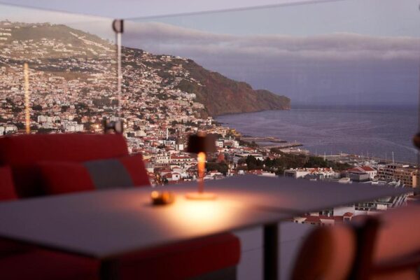 Outdoor terrace at dusk overlooking a coastal town on hills and the sea