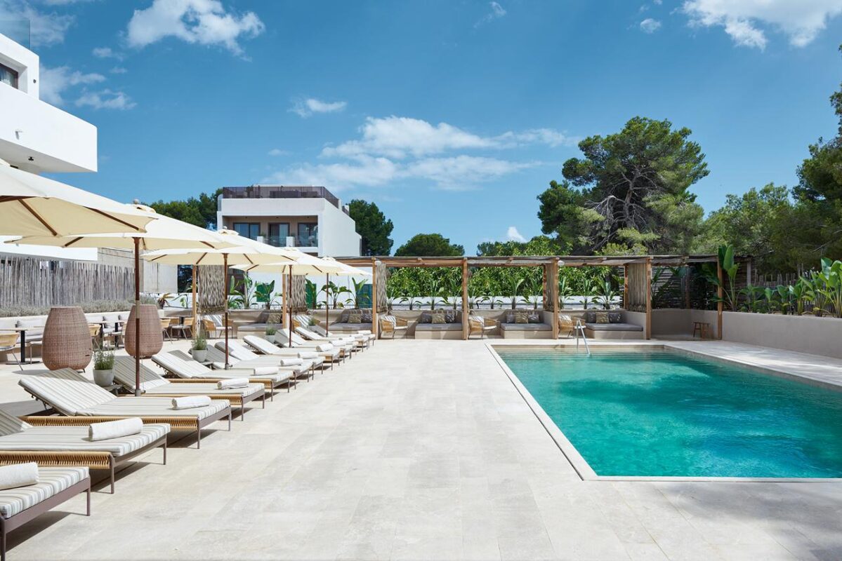 Outdoor luxury pool area with white lounge chairs, umbrellas, and cabana seating at a modern resort.