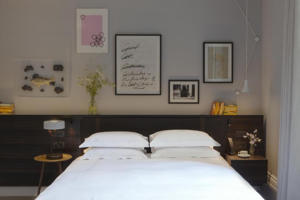 Modern hotel-style bedroom with a white bed, dark wooden headboard, and multiple framed artworks above the headboard.