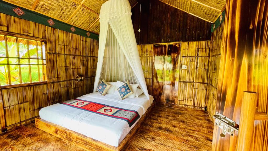 Bedroom in a bamboo hut with a queen-size bed, white linens, and a sheer canopy netting above the bed