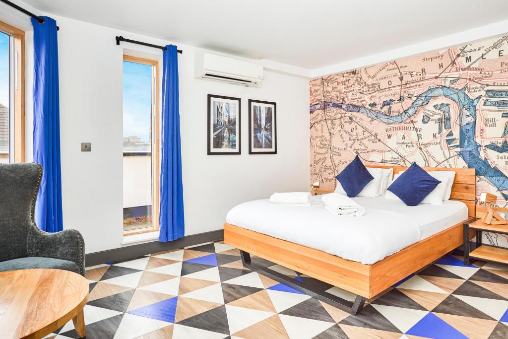 Bedroom with a wooden platform bed, blue pillows, and a map-themed wall accent in a bright hotel room.