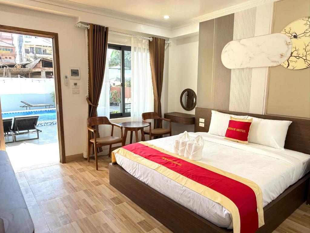 Hotel room with a large bed, red-gold runner, and folded towel art near the center; sliding door to an outdoor pool area.