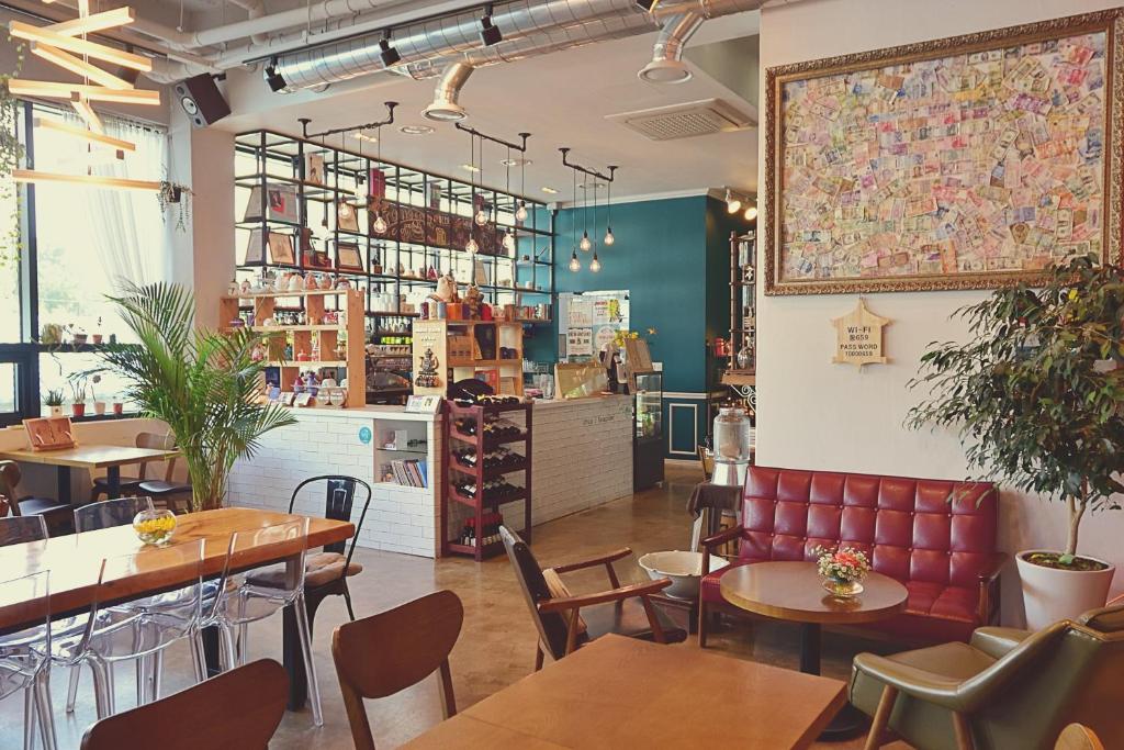 Bright cafe interior with a white-tiled counter, wooden tables, clear chairs, potted plants, and a large map artwork on the wall.