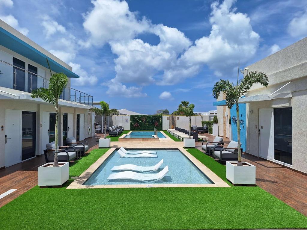 Hotel pool courtyard with two parallel pools, white lounge chairs, and palm trees under a bright blue sky.