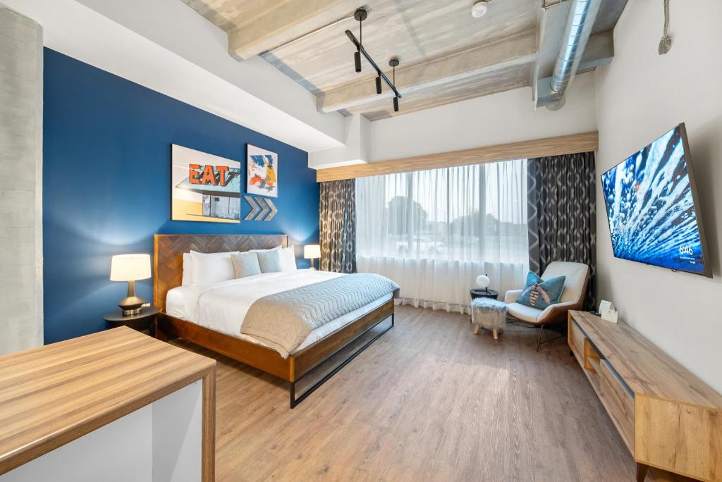 Hotel room with a blue feature wall behind a wooden bed, white bedding, and bedside lamps.