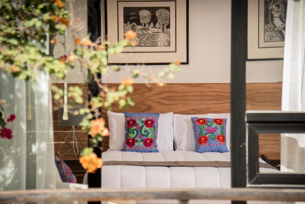 White sofa with embroidered blue cushions in a sunlit living room with a wooden panel wall and framed art above it.