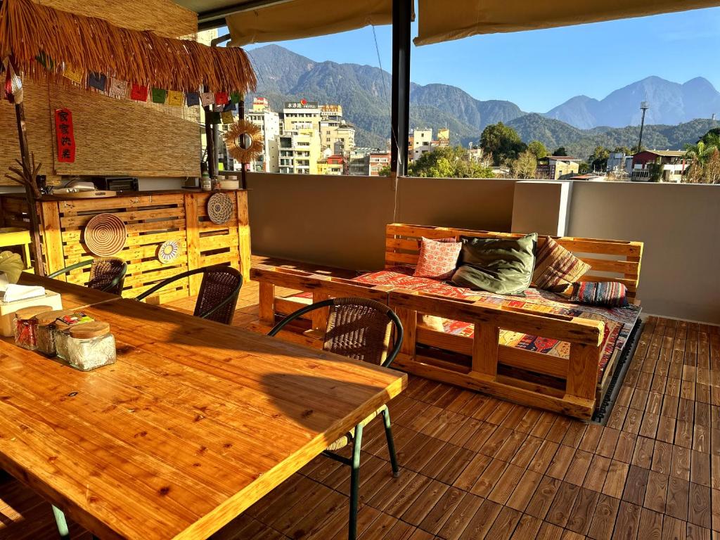 Rooftop patio with wooden sofa and table, colorful cushions, a bar area, and distant mountain views.