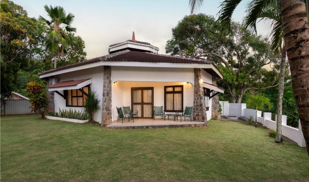 Single-story cottage with stone columns, covered porch, and outdoor seating on a grassy lawn.