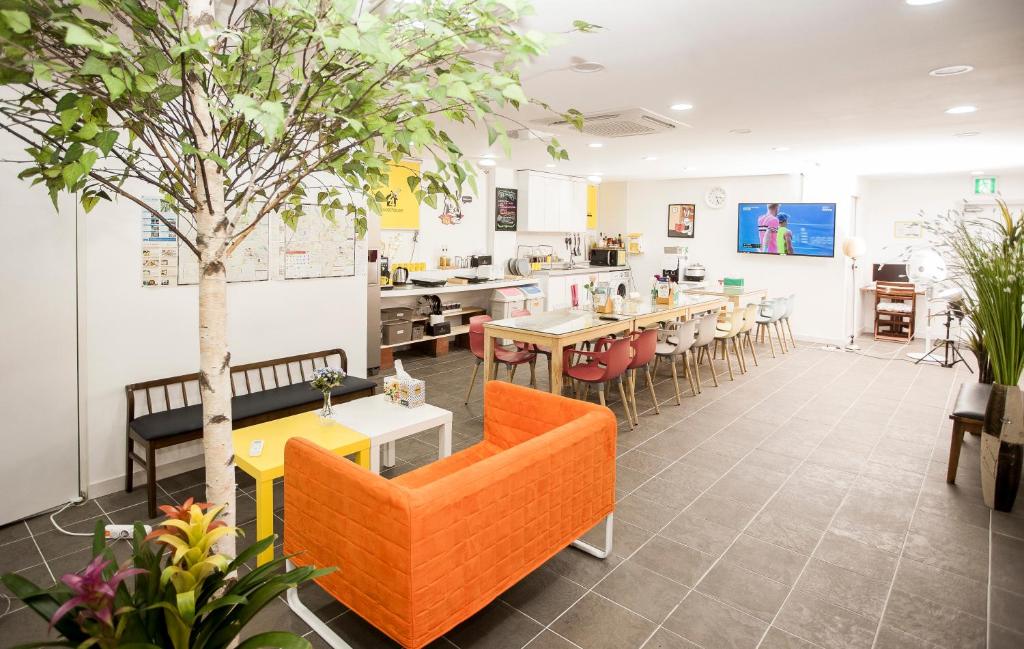 Bright, modern break room with an orange sofa, a long communal table, and green plants in a spacious lounge area.