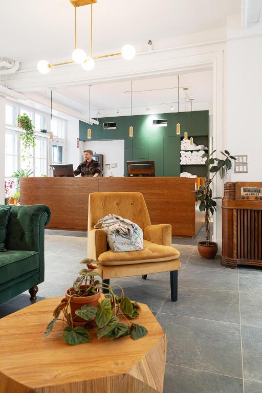 Lobby reception with a wooden front desk, a man working on a laptop, and a green accent wall behind him.