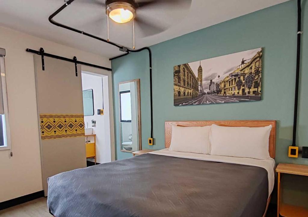 King bed in a modern bedroom with teal accent wall, wooden headboard, two nightstands, and cityscape wall art above the bed.
