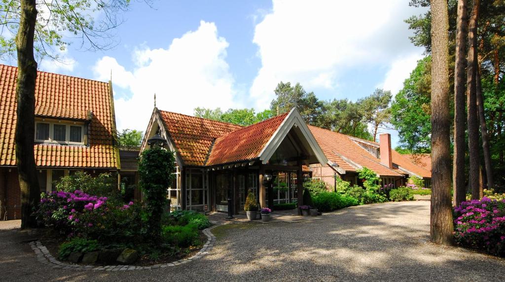 Brick buildings with red-tiled roofs form a garden courtyard, a gravel path winding between greenery and trees.