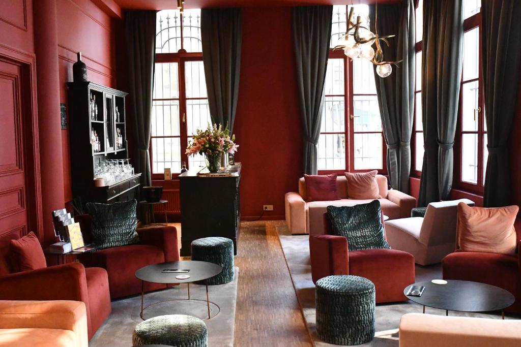 Luxurious lounge with red walls, velvet red seating, dark curtains, and a bar area with a flower arrangement.