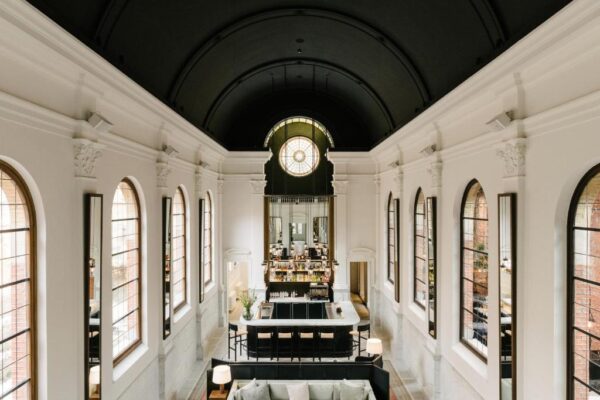 Bright airy cafe interior with high arched windows, white pillars, and a central bar scene