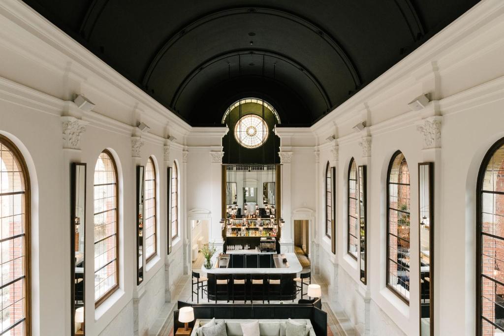 Bright airy cafe interior with high arched windows, white pillars, and a central bar scene