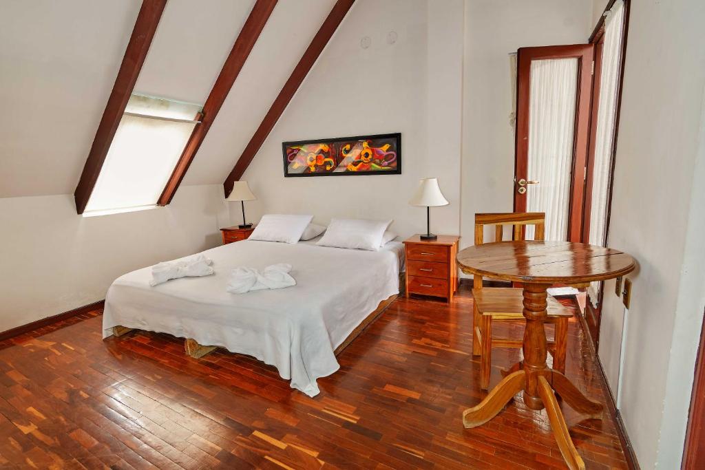 Cozy attic bedroom with a double bed, white linens, and matching nightstands under slanted wooden beams.