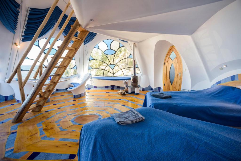 Whimsical bedroom with blue bedding, wooden ladder to a loft, curved wooden door, and stained-glass window.” (informative image)
