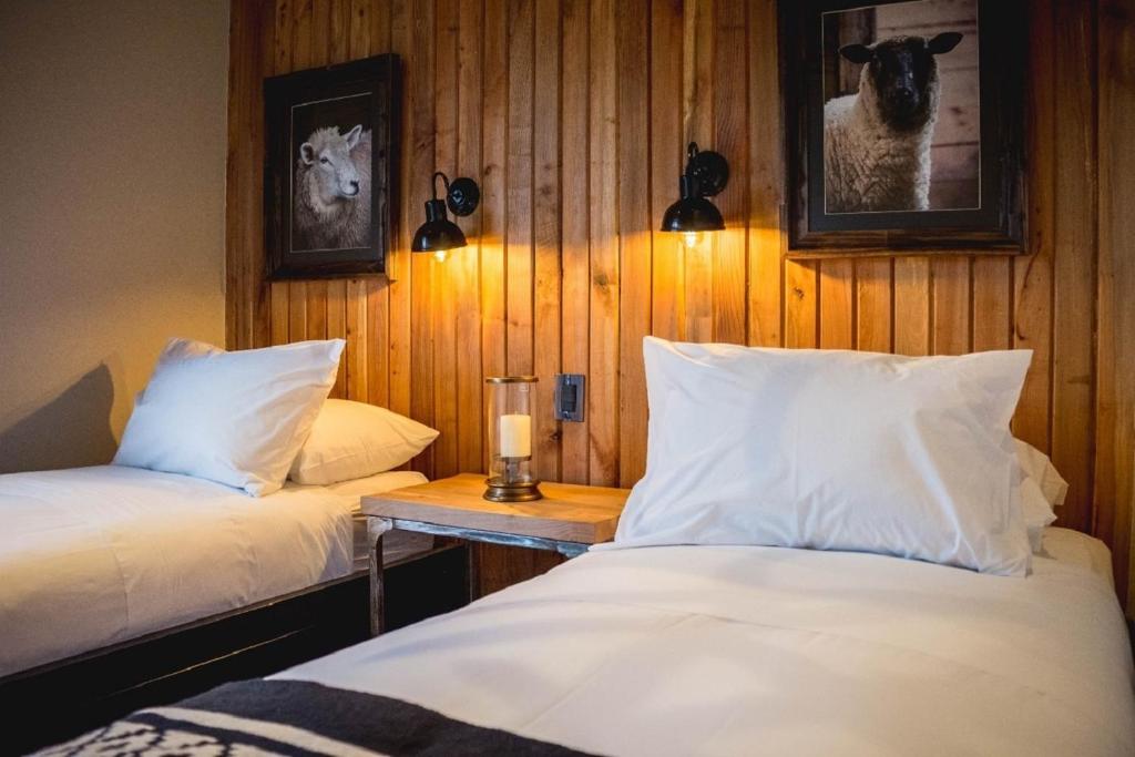 Two single beds with white linens and a wooden wall, a shared nightstand with a candle between them.