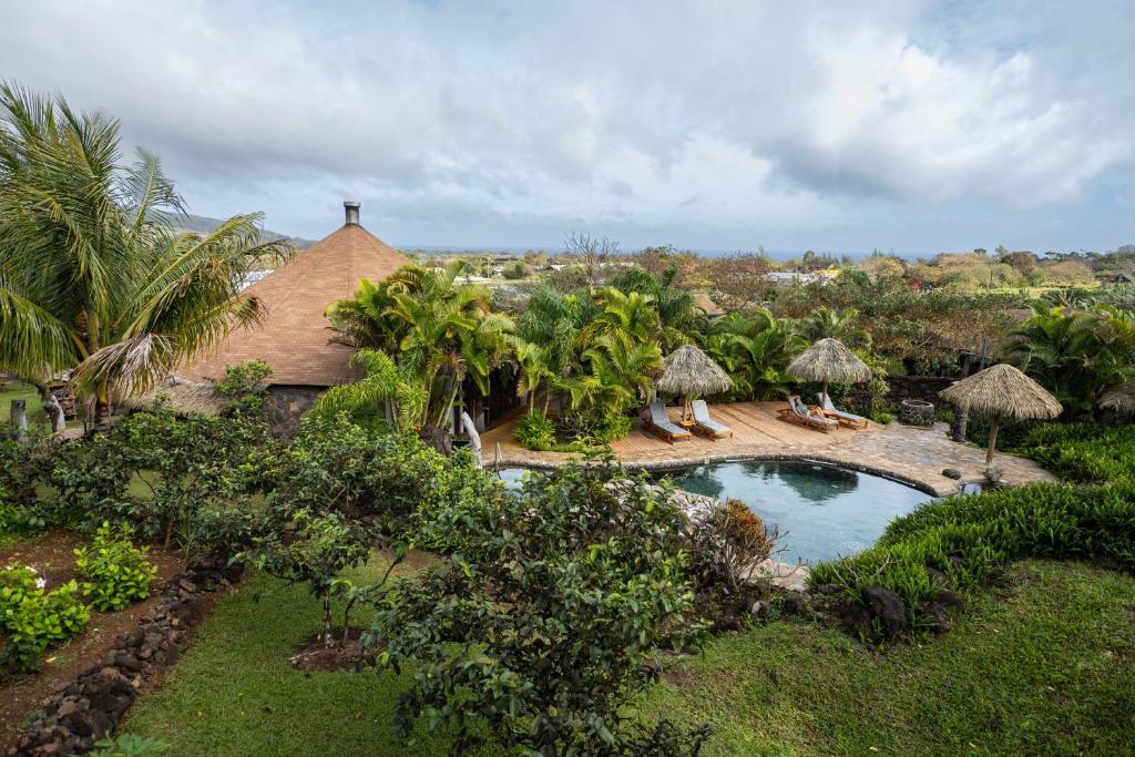 Tropical resort pool area with a wooden deck, thatched umbrellas, lounge chairs, and lush palm trees.
