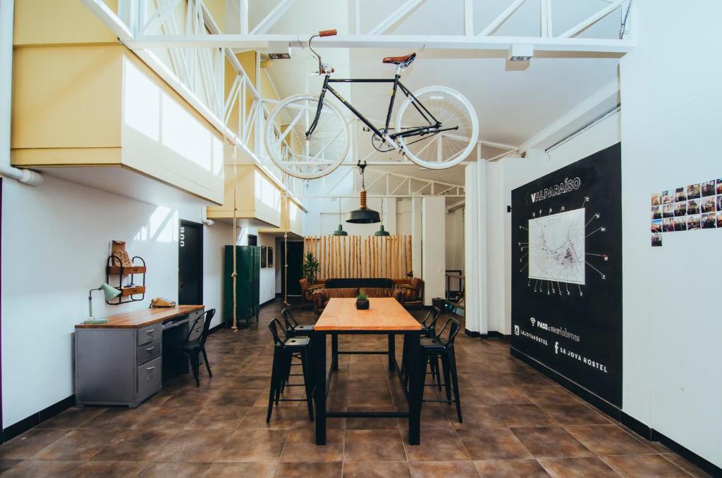 Industrial-style coworking space with a long wooden table, black chairs, and a bicycle hanging from the ceiling.
