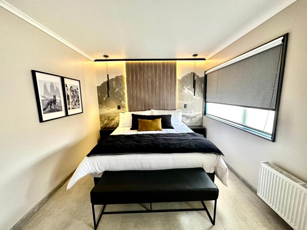 Modern hotel bedroom with white bedding, black accent pillows, and a black bench at the foot of the bed.