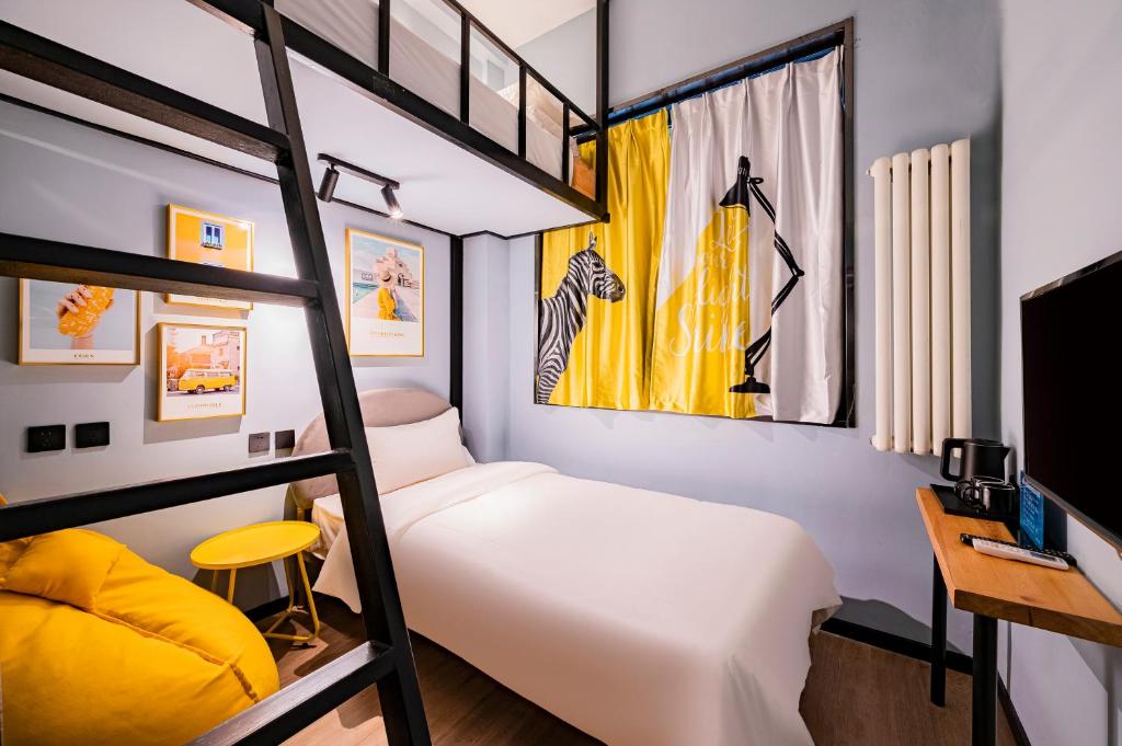 Bedroom with white bed under a black loft frame, yellow accents, and framed art on the wall.