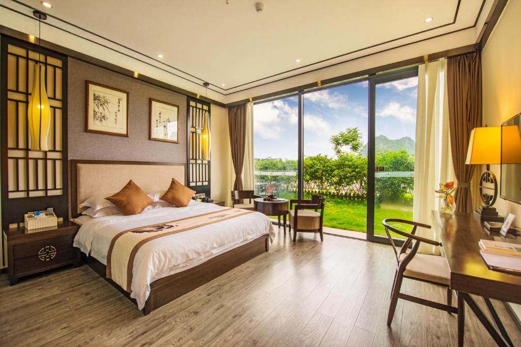 Hotel room with a king bed, dark wood headboard, and large glass doors opening to a green garden view.