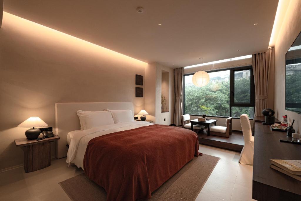 Hotel room with a large bed, white linens, and a warm brown duvet; bedside lamps glow softly.