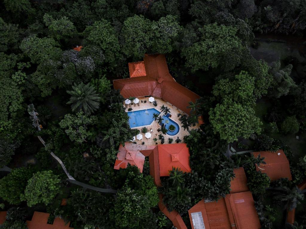 Aerial view of a tropical resort with red-roof buildings surrounding a central blue pool.