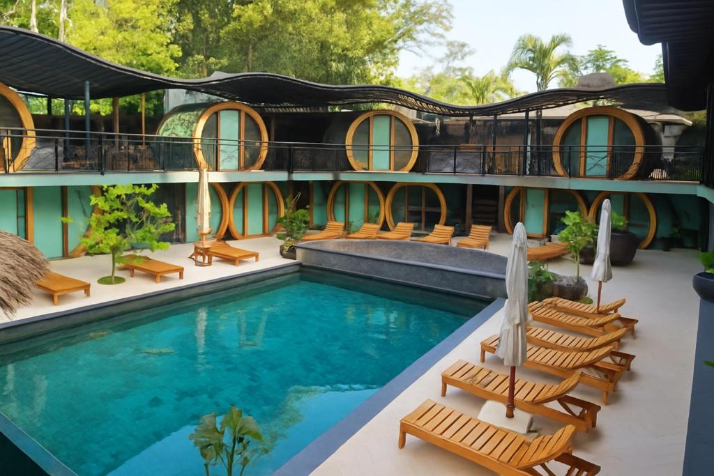 Poolside view of a turquoise rectangular pool, wooden sun loungers, and circular pod-style rooms along a two-story courtyard.