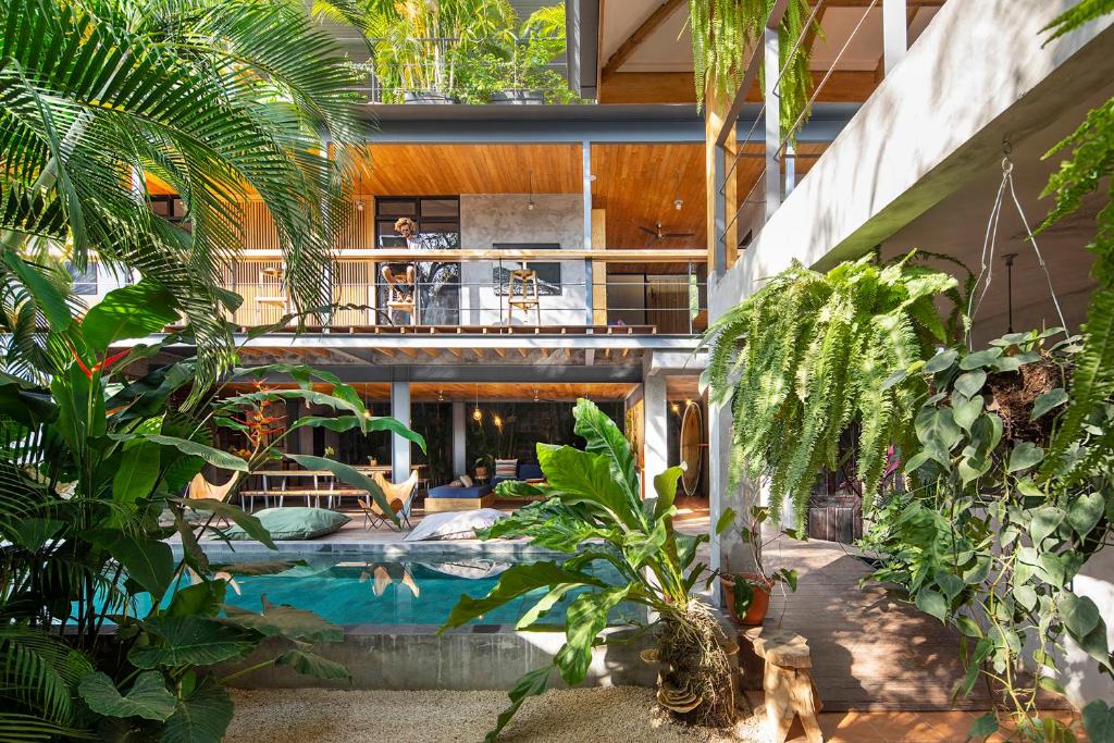 Open-air courtyard with a rectangular pool, tropical plants, and a two-story home with wooden balconies.