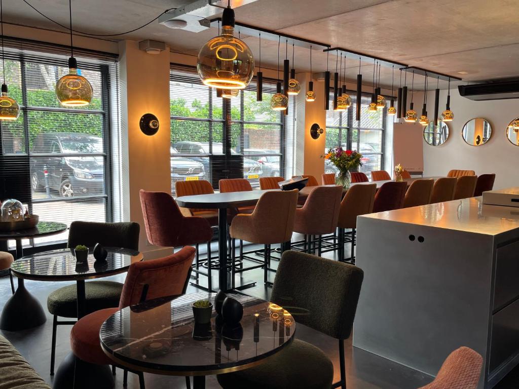 Modern cafe interior with round marble tables, colorful upholstered chairs, and warm pendant lighting.