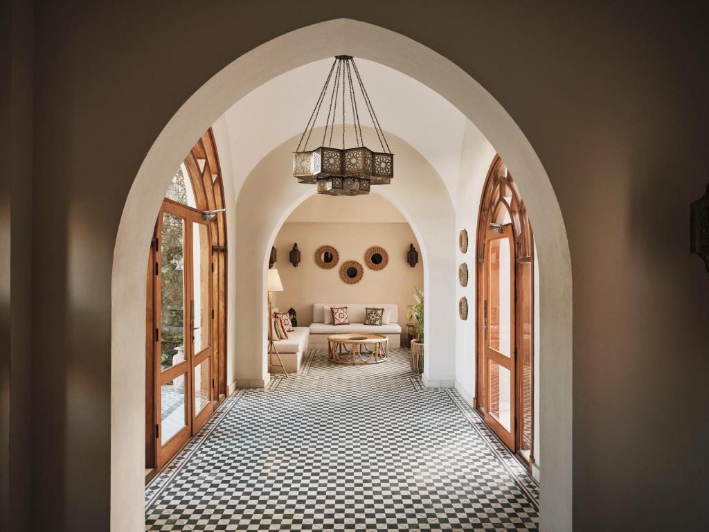Arched doorway opening to a sunlit living room with a checkered floor and beige sofa.