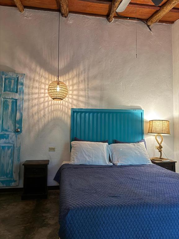 Blue upholstered headboard over a white-presh bed with white pillows in a rustic bedroom.