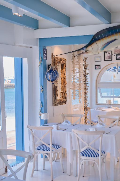 Bright seaside restaurant interior with white tables and blue-striped chairs, nautical decor and windows overlooking the sea,