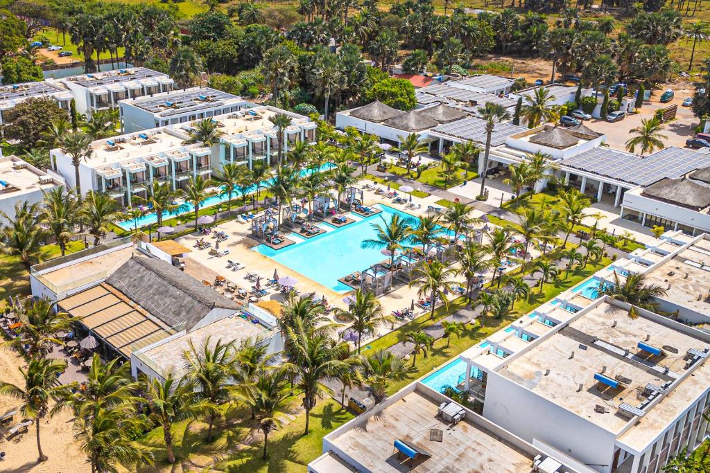 Aerial view of a tropical resort with multiple turquoise pools, white low-rise buildings, and palm trees.
