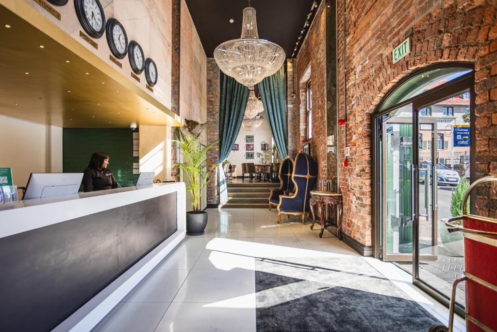 Hotel lobby reception desk on the left with a receptionist, brick walls and a chandelier overhead.