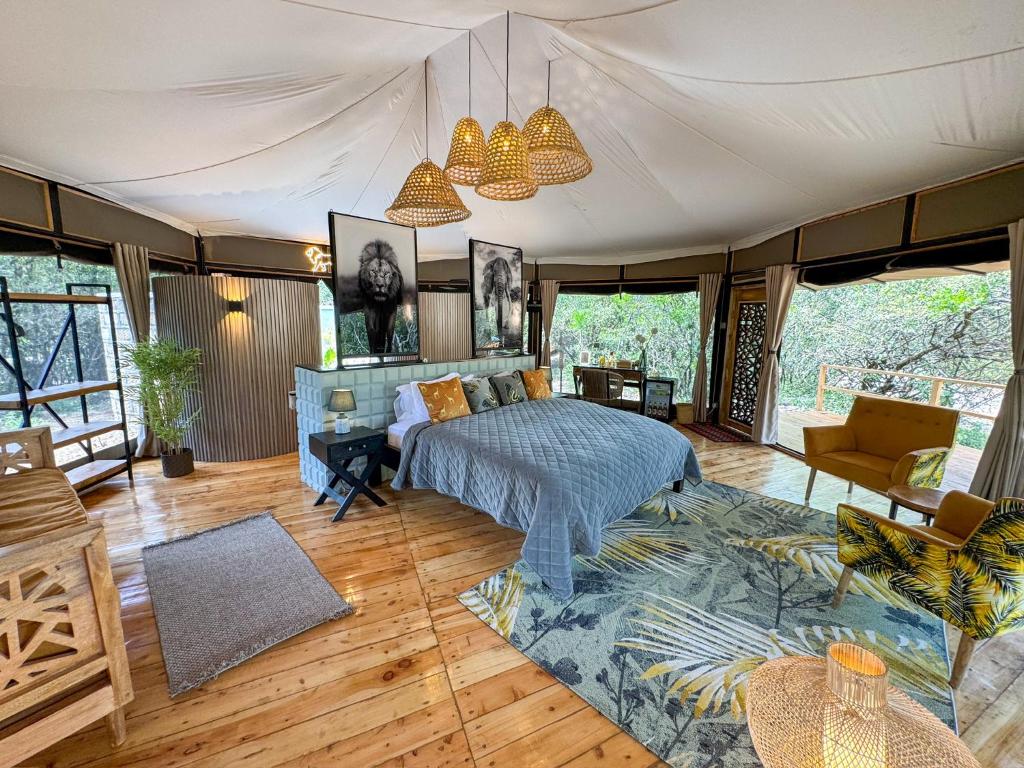 King-size bed with a gray quilt and yellow throw pillows in a tented bedroom, wood floor and woven pendant lights overhead.