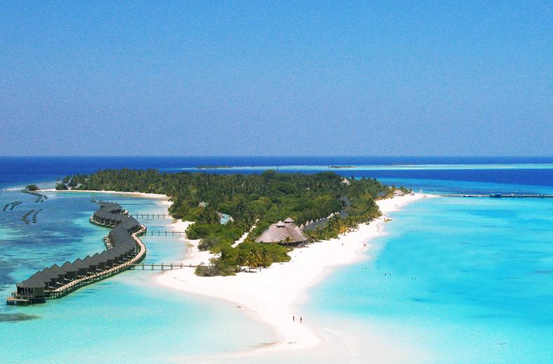 Tropical island with white sand, turquoise water, and overwater bungalows lining a palm-covered island.