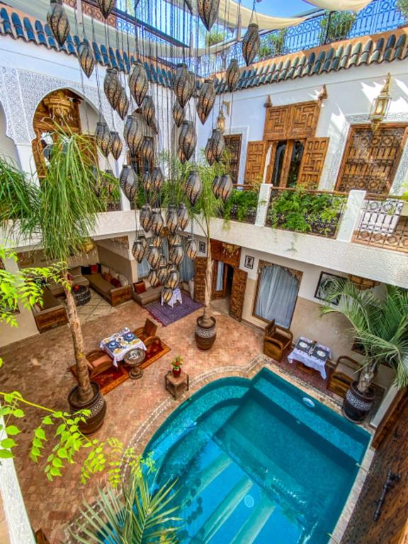 Interior courtyard with a blue-tiled pool, surrounding seating, and hanging Moroccan-style lanterns above.