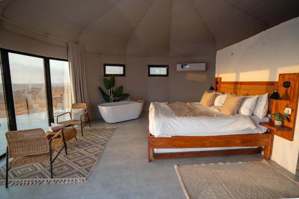 Spacious bedroom with a wooden-framed king bed, white bedding, and a wooden headboard, bedside lamps, and a small plant on the wall shelf.