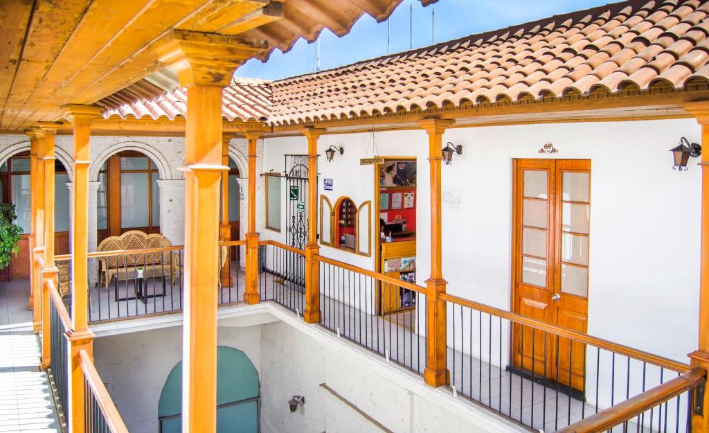 Open-air courtyard with orange wooden columns, white walls, and terracotta-tiled roof; a reception window is visible ahead.