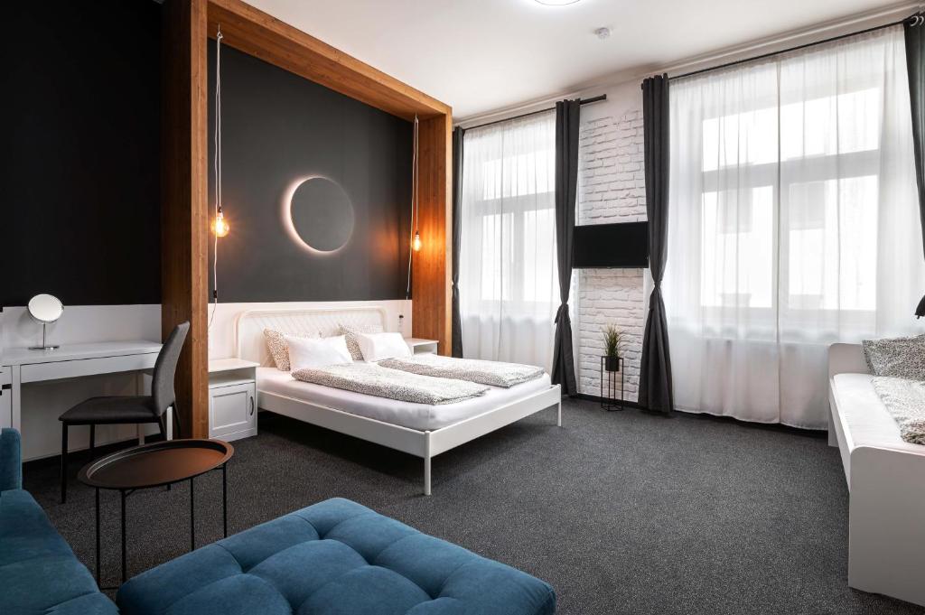Hotel room with a white bed under a dark accent wall, wood frame, and warm pendant lights.