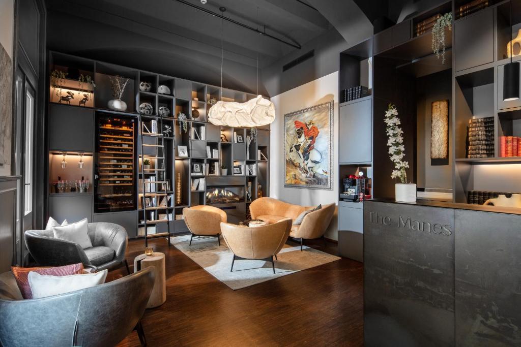 Luxurious dark lounge with curved tan chairs around a light rug, flanked by floor-to-ceiling shelves and a modern bar area.