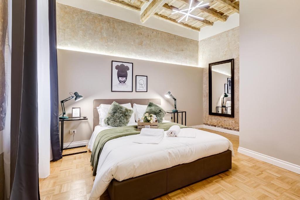 Modern hotel-style bedroom with a low brown bed, white bedding, green throw pillows, two black bedside lamps, and a wooden floor.
