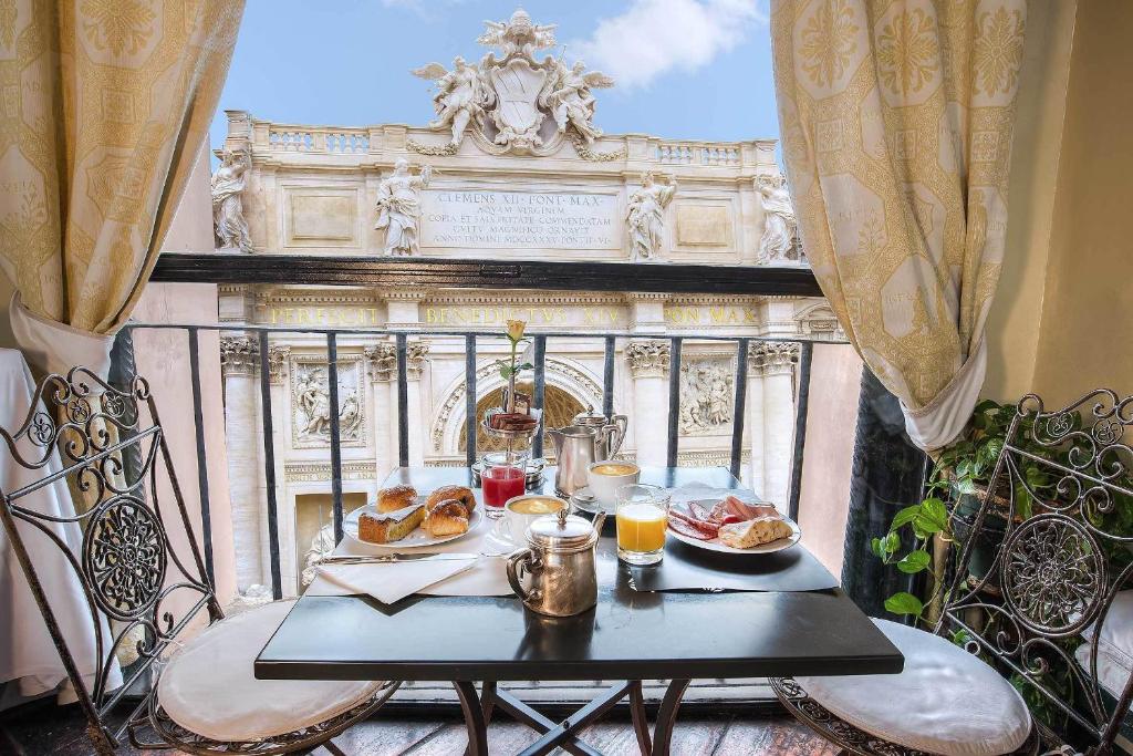 Breakfast for two on a wrought-iron balcony with pastries, juice, and coffee, overlooking an ornate historic façade.