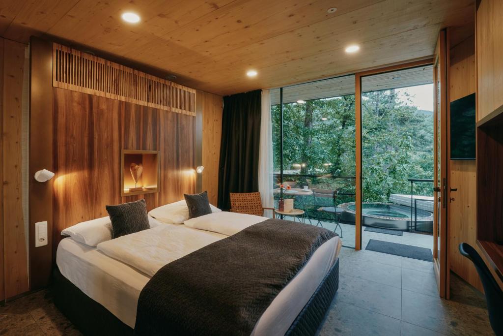 Hotel room with two twin beds pushed together, wood-paneled headboard, and a balcony with seating and a hot tub outside.
