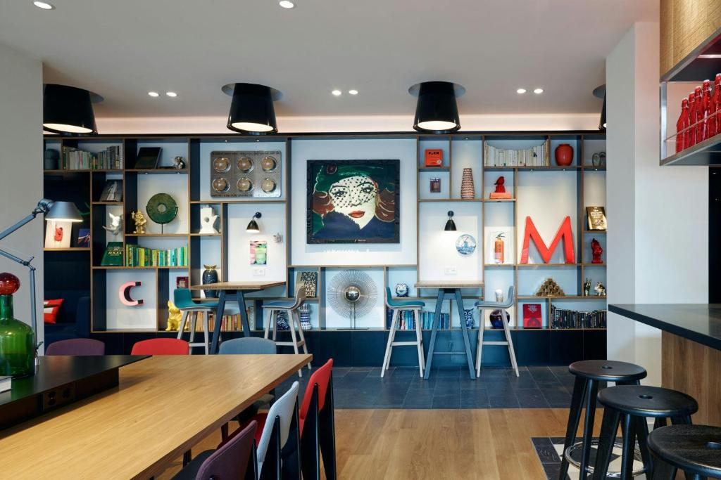 Contemporary cafe seating area with a wall of decorative shelves, artwork, and a red letter M centerpiece.