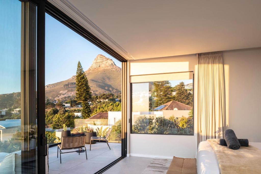 Bright hotel room with large sliding glass doors opening to a balcony, showing a mountain and trees outside.